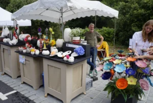 Vente d'artisanat en céramique et décoration florale, marché artisanal à La Pepiterre avec céramiques colorées et sculptures florales, ambiance conviviale et créative.