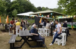 Un rassemblement familial et amical lors d'un événement en plein air avec des gens de tous âges, sous pavillons et décorations colorées, profitant d'une ambiance chaleureuse.